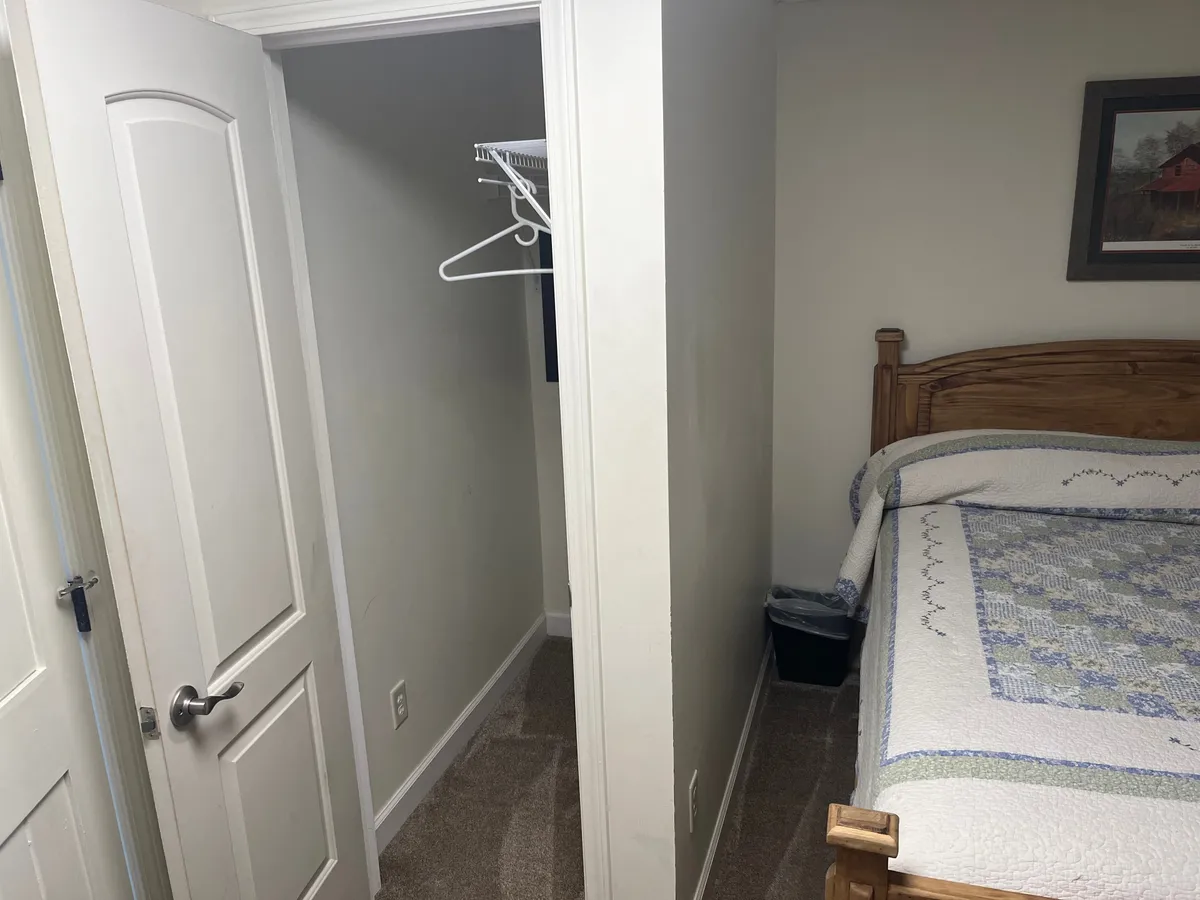 A comfortable bedroom scene with a soft bed, a closet for storage, and a framed picture adding a touch of personal flair. The room feels serene, perfect for reading, sipping morning coffee, or enjoying quiet moments.